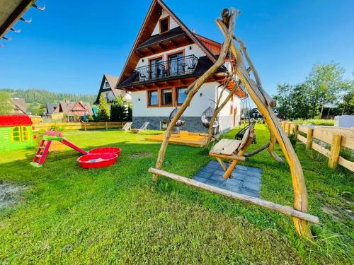 a house with a playground with a swing at Gąsienicowy Widok in Poronin
