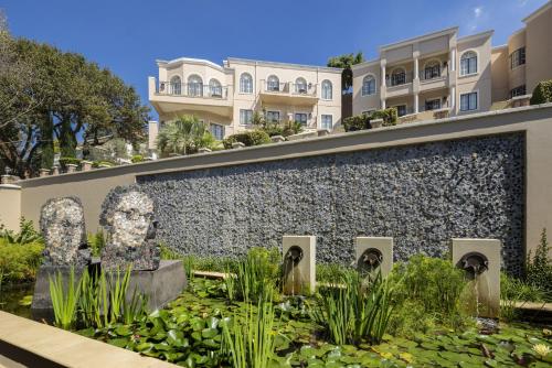 a garden with a statue in front of a building at Four Seasons Hotel The Westcliff in Johannesburg