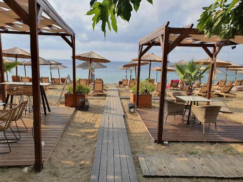 a wooden deck with tables and umbrellas on the beach at Azure Breeze - Coastal Chic Getaway by the Sea in Psakoudia