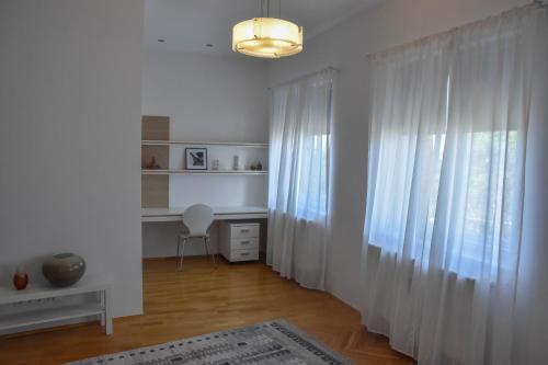 Furmint & Juhfark Apartmanok في فيسبرم: غرفة بيضاء مع ستارة ومكتب ونافذة