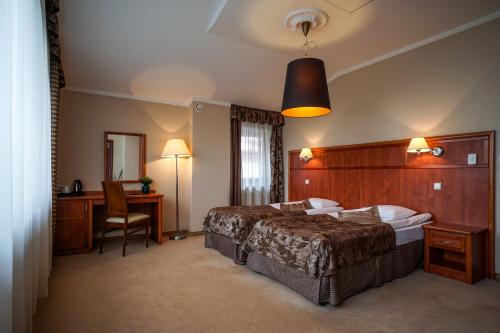 a hotel room with a large bed and a desk at Farmona Hotel Business & SPA in Kraków