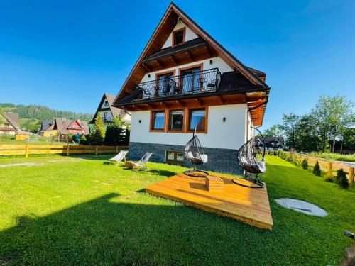 a house with a balcony on top of a yard at Gąsienicowy Widok in Poronin