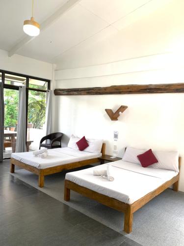 2 camas en una habitación con paredes y ventanas blancas en Heart of Mother Earth (HOME) Resort en Aringay