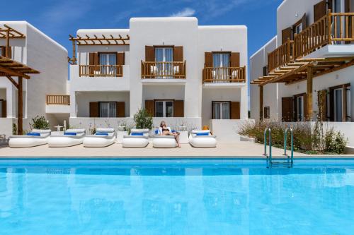 a woman sitting on a chair next to a swimming pool at Mykonaki Hotel in Ano Mera