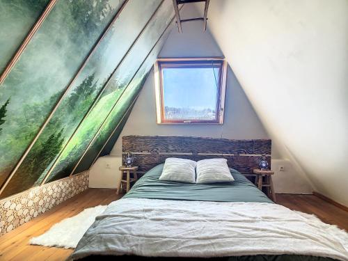 - une chambre avec un lit et une fenêtre mansardée dans l'établissement Le Grenier du Buronnier, à Saint-Simon