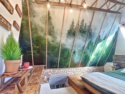 une chambre avec une grande fresque murale représentant une forêt dans l'établissement Le Grenier du Buronnier, à Saint-Simon