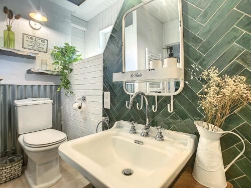 une salle de bain avec un lavabo, des toilettes et un miroir dans l'établissement Le Grenier du Buronnier, à Saint-Simon