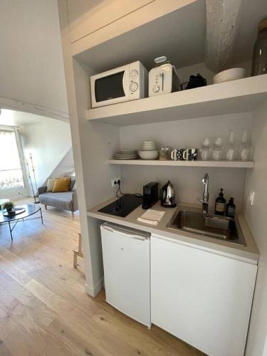 une cuisine avec un évier et un micro-ondes dans l'établissement Magnifique studio - Louvre Opéra, à Paris