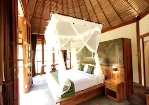 1 dormitorio con 1 cama con mosquitera en Bali Jungle Taksu, en Tampaksiring