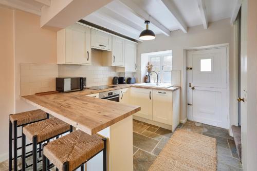a kitchen with white cabinets and a wooden counter top at Host & Stay - Dale End in Kirkbymoorside