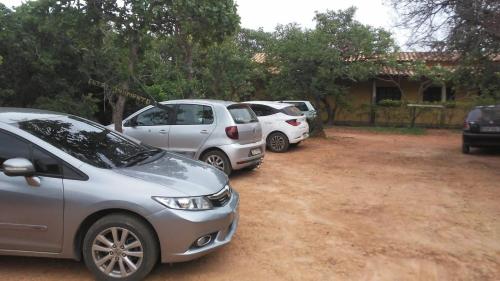 three cars parked in a dirt lot in front of a house at Pousada Caminho in Serra do Cipo