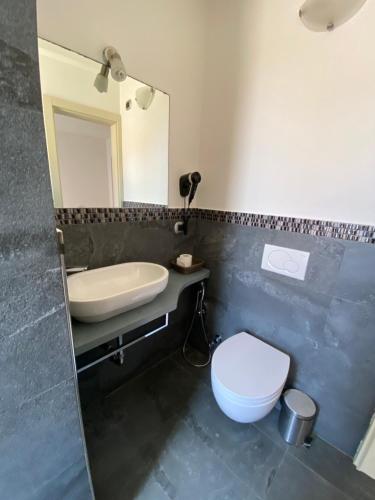 a bathroom with a sink and a toilet and a mirror at Pensione Sorriso in Vernazza
