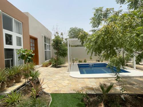 Little Garden private pool villa في Al Ḩamrāʼ: منزل فيه مسبح في ساحة