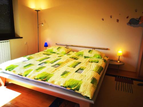a bed with a yellow and green comforter in a bedroom at Apartment Sončni Mokec in Rečica ob Savinji