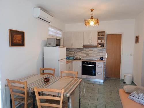 una cucina con tavolo e frigorifero bianco di Apartments Suha Punta - Crnic a Rab