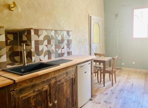 uma cozinha com um balcão, um lavatório e uma mesa em Chambres et gîte en Cévennes em Cros