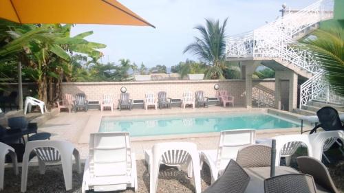 a swimming pool with chairs and a table and an umbrella at Résidence Hôtelière l'Océane in Kribi