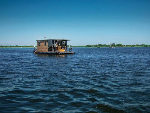 un petit bateau au milieu d'une grande masse d'eau dans l'établissement Nice houseboat in Kinrooi for rent, à Kinrooi