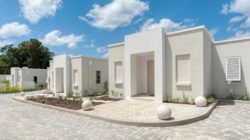 a row of white buildings on a brick road at Unforgettable 3BR Luxury Villa at Porter's Place in Saint James