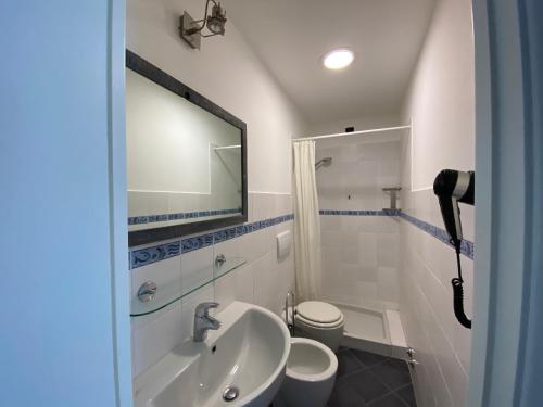La salle de bains est pourvue d'un lavabo, de toilettes et d'un miroir. dans l'établissement Pensione Sorriso, à Vernazza