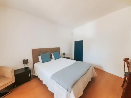 a bedroom with a large white bed with blue pillows at O Conventinho in Évora