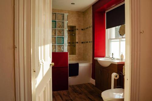 a bathroom with a toilet and a sink and a tub at Manorbier House - St Anne's Room in Tenby