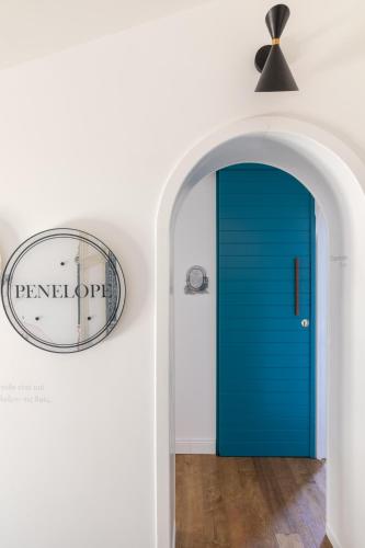 a blue door in a white room with a clock at Giardini Penelope Resort e Spa in Ciampino
