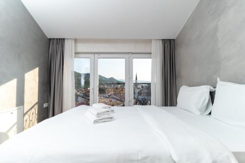 una camera da letto con un grande letto bianco con una grande finestra di Ornament Hotel and Apartments a Sarajevo
