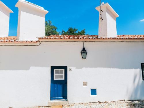 a white building with a blue door at O Conventinho in Évora
