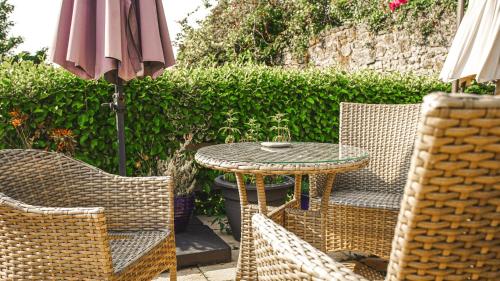 a patio with a table and chairs and an umbrella at Manorbier House - St Anne's Room in Tenby