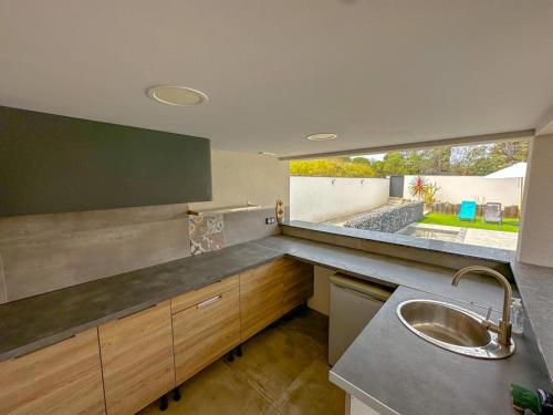 une cuisine avec un évier et une grande fenêtre dans l'établissement L'Attrape Rêves, à Villelongue-dels-Monts