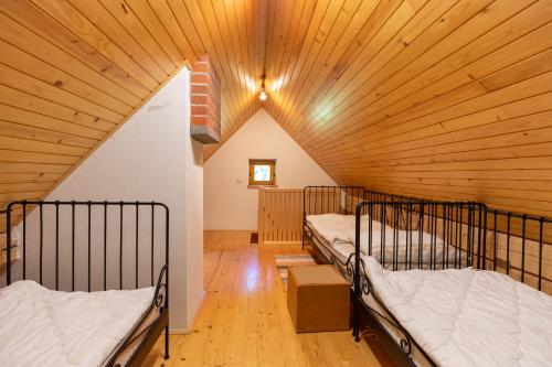 two beds in a room with a wooden ceiling at Mala hiša in Solčava