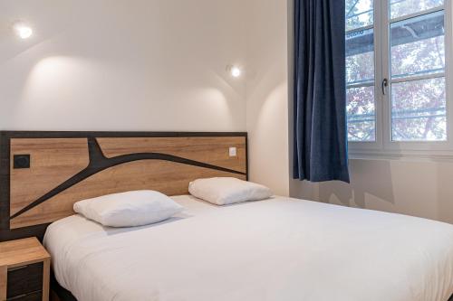 a bed with two pillows in a room with a window at Croix Paquet - Appartements à Lyon in Lyon