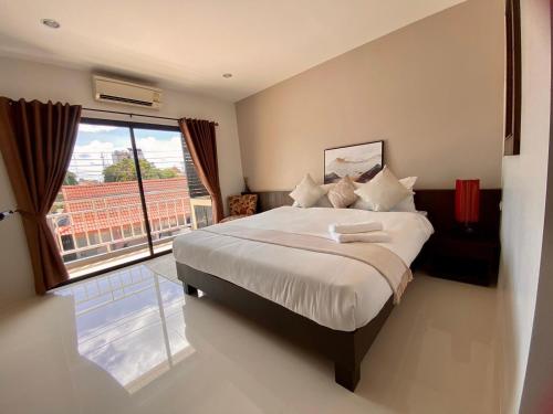um quarto com uma cama grande e uma janela grande em SD Residence I Naiyang Beach I HKT Airport em Ban Bo Han