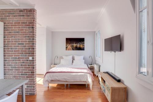 a white bedroom with a bed and a brick wall at Eiffel Tower view terrace Saint Germain des Pres in Paris