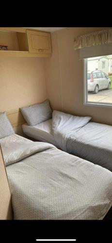 three beds in a small room with a window at S452 Golden Palm Resort in Chapel Saint Leonards