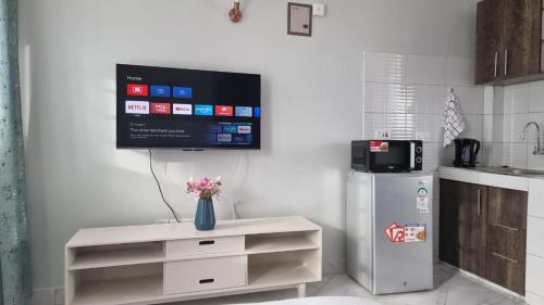 a kitchen with a tv on a wall with a refrigerator at Studio 47 Ensuite Apartment in Donholm Phase 5G Estate, Nairobi in Nairobi