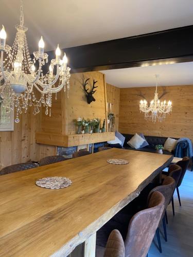 a dining room with a large wooden table and chandeliers at Chalet le Bô & Spa in Bussang