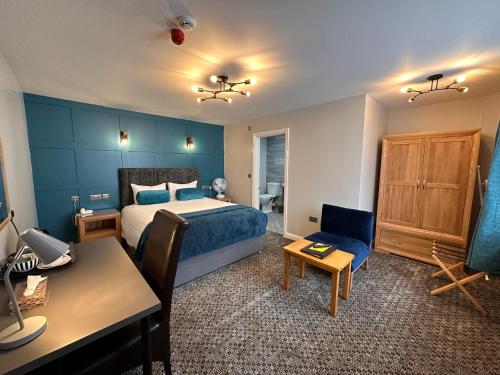 een slaapkamer met een bed, een bureau en een stoel bij Spilman Hotel in Carmarthen