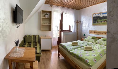 a bedroom with a bed and a table and a television at Penzion pod Tatrami in Ždiar