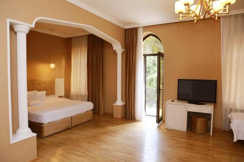 1 dormitorio con 1 cama y TV en Deluxe Hotel Ganja, en Ganja