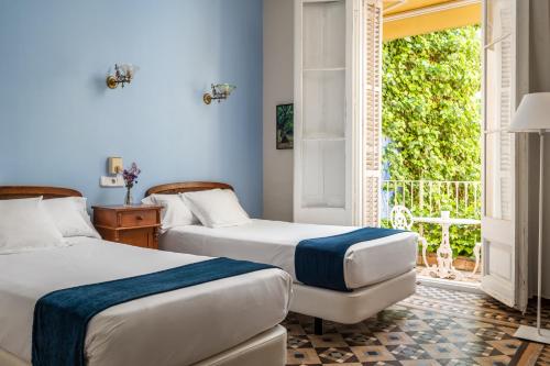 two beds in a room with a window at Hotel Medium Renaixen&ccedil;a in Sitges