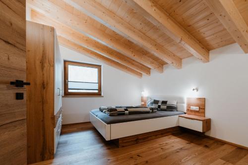 una camera con letto in una stanza con soffitti in legno di Apart GuetGeanLossn a Längenfeld