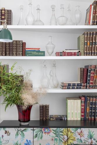 a shelf filled with white vases and books at Giardini Penelope Resort e Spa in Ciampino