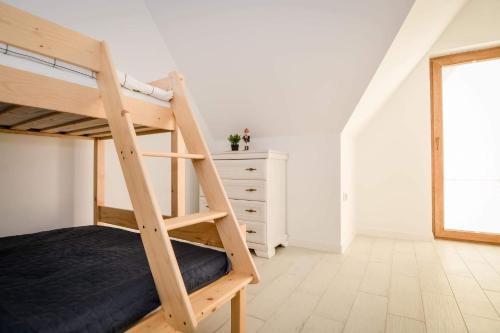 a bedroom with a bunk bed with a ladder at Domek za rondem in Ratułów