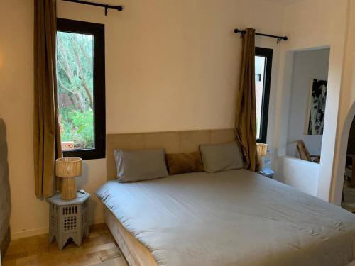 a bed in a room with two windows at Offrez-vous un moment de détente in Marrakesh