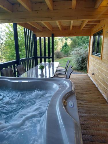 a hot tub on a deck with a table and chairs at Le Village des Monédières in Chamberet
