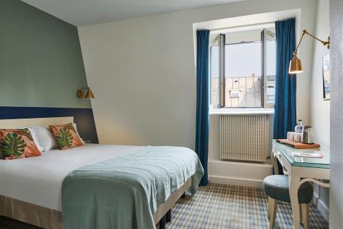 Hotel Etoile Saint Ferdinand by Happyculture في باريس: غرفة نوم بسرير ومكتب ونافذة