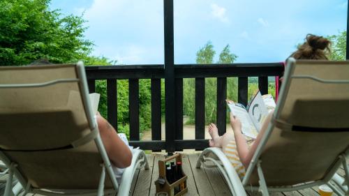 two people sitting in lawn chairs on a porch at Le Village des Monédières in Chamberet