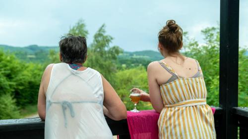 two women sitting at a table with a glass of wine at Le Village des Monédières in Chamberet